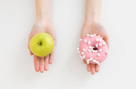 Close up hands holding doughnut and apple
