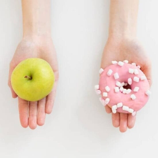 Close up hands holding doughnut and apple