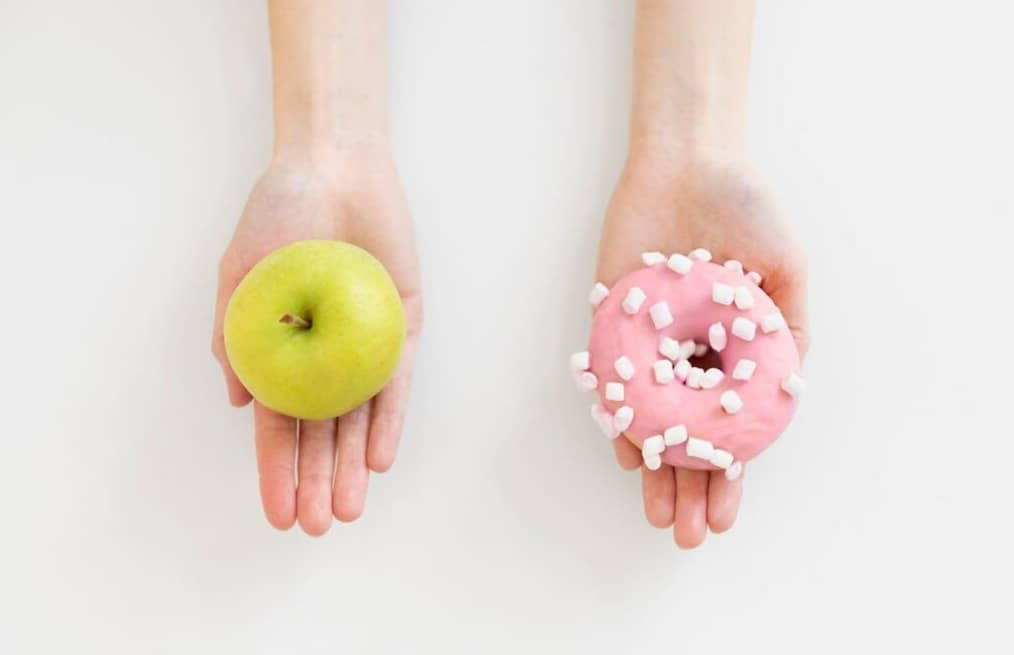 Close up hands holding doughnut and apple